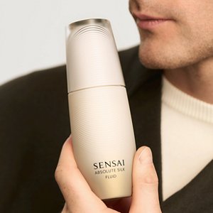 Eine Nahaufnahme des Models, das die Absolute Silk Fluid Flasche in der Hand hält